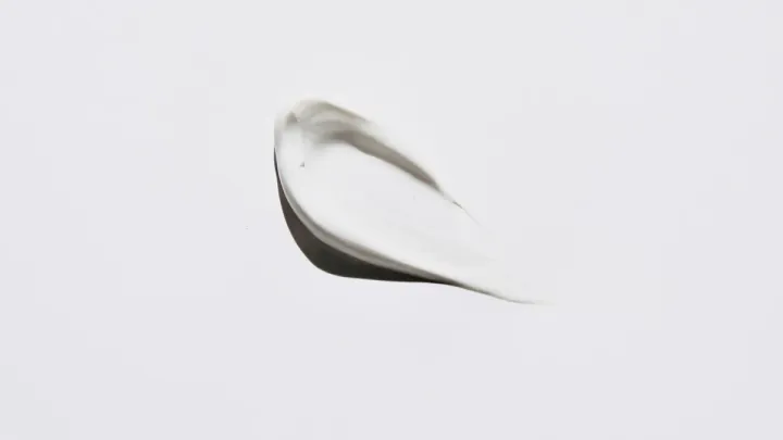 Pincelada de crema blanca sobre un fondo gris claro