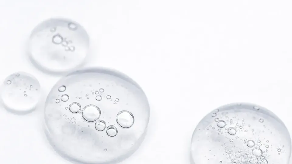 Gotas de sérum de niacinamida sobre superficie de cristal transparente