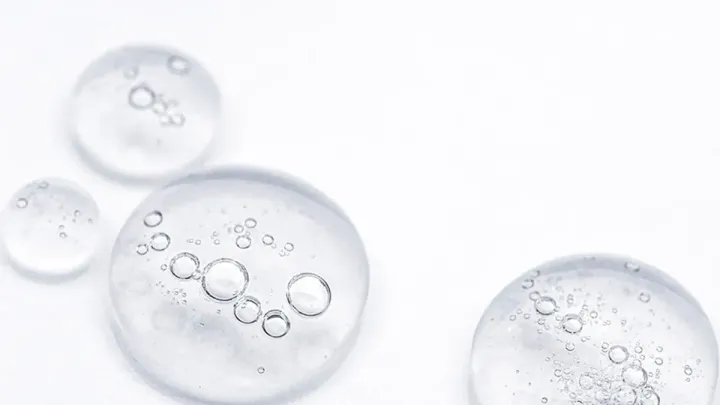 Gotas de sérum de niacinamida sobre superficie de cristal transparente