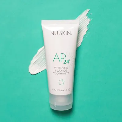 Tubo de pasta de dientes AP24 Whitening Fluoride Toothpaste de Nu Skin sobre fondo verde