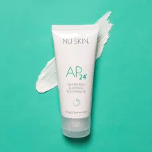 Tubo de pasta de dientes AP24 Whitening Fluoride Toothpaste de Nu Skin sobre fondo verde