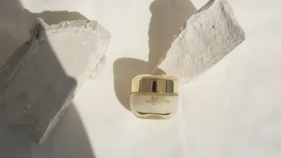 Tarro de crema blanco sobre una mesa clara, en tonos beige y minimalistas